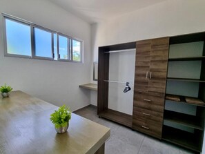 A room with a wooden table, a potted plant, a wardrobe with a mirror, and a window with blinds. - Modern Rutelena Villa, sleeps 12, private pool, 5 min to 5th Street, the beach, and the supermarket (playa del carmen)