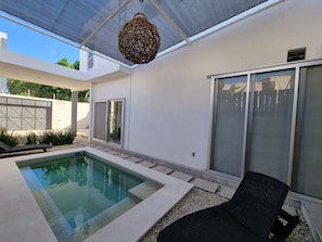 A modern outdoor pool area with a clear pool, a lounge chair, and a pergola overhead. - Modern Rutelena Villa, sleeps 12, private pool, 5 min to 5th Street, the beach, and the supermarket (playa del carmen)
