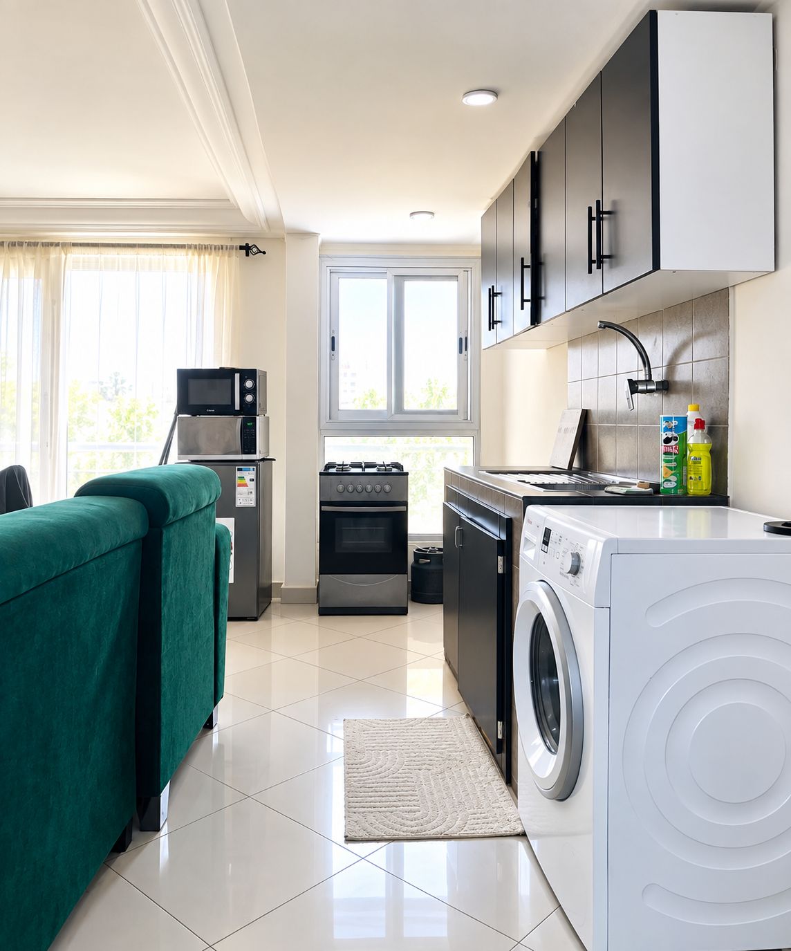 A compact kitchen with a washing machine, a microwave, and a stove.
