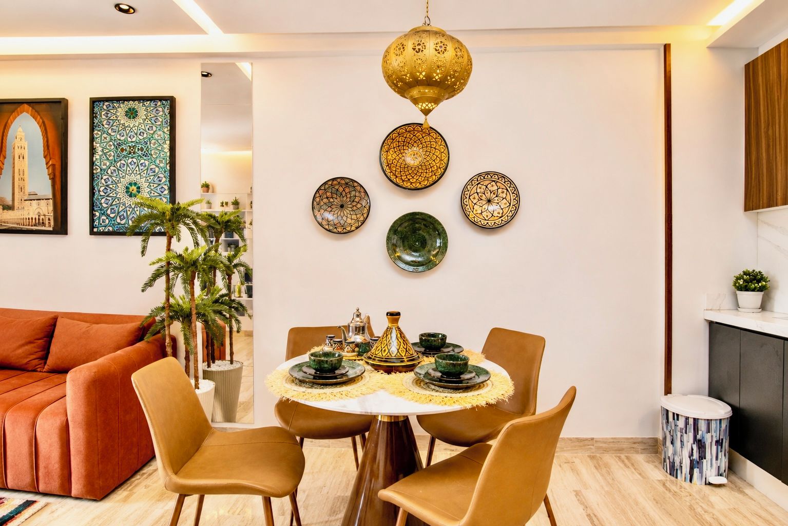 A dining area with a round table, chairs, and a decorative wall with plates and a hanging lamp.
