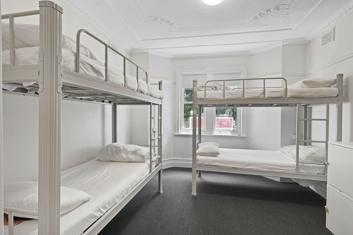 Un dormitorio tipo cabina con dos literas, una ventana y techo blanco.