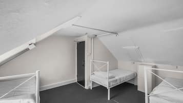 Ein Schlafsaalzimmer mit drei Etagenbetten, einem Oberlicht und einer Tür zu einem weiteren Raum.