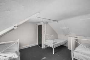 A dormitory room with three bunk beds, a skylight, and a door leading to another room. - Serene Hostels Potts Point (Potts Point)