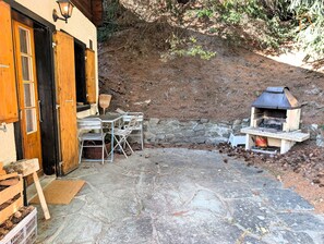 A rustic outdoor seating area with a stone patio, a wooden door, and a wood-fired oven. - Charming chalet near the funicular for 5-6 peopleOutside: detached chalet near the funicular with la (St-Luc)