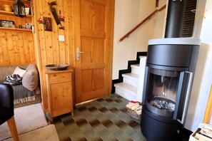 A cozy room with a wooden door, a black wood stove, a staircase, and a small wooden cabinet with a bowl on top. - Charming chalet near the funicular for 5-6 peopleOutside: detached chalet near the funicular with la (St-Luc)