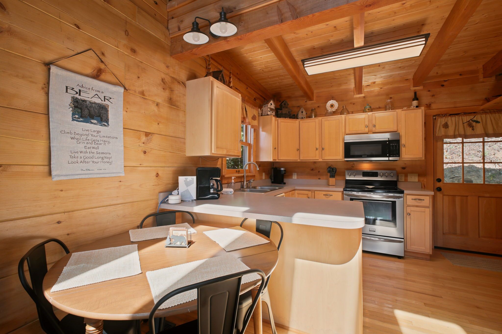 L’int érieur d’un chalet en bois comprend une cuisine, un coin repas et une affiche accrochée au mur.