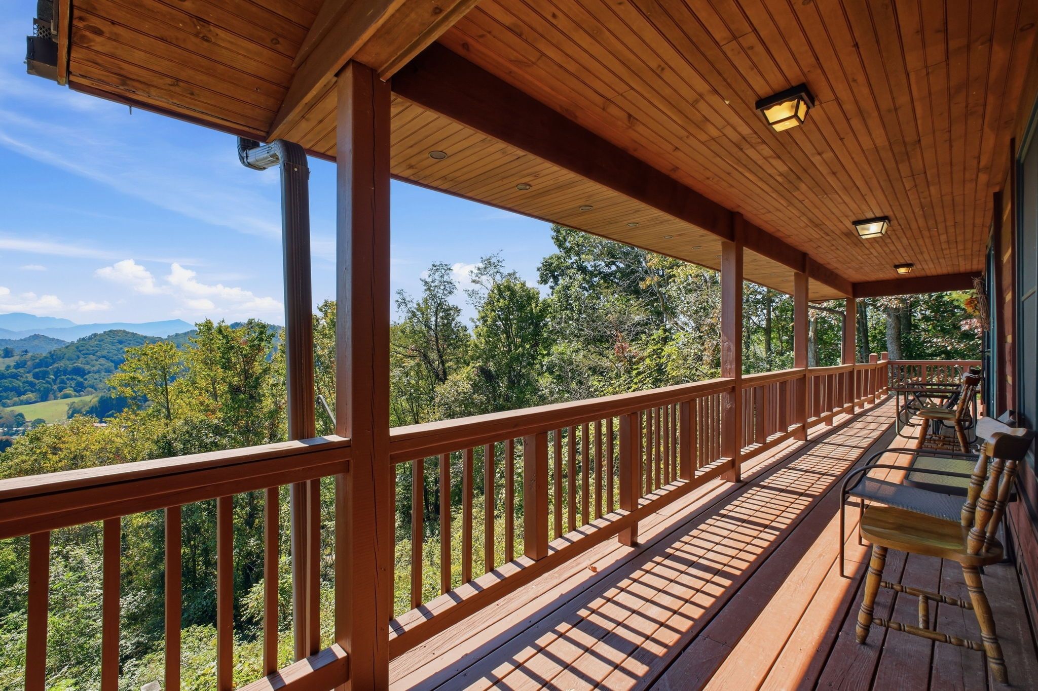 A wooden deck with a railing overlooking a mountainous landscape.