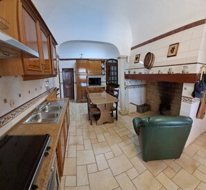 A kitchen with a dining area, a fireplace, and a green leather chair.