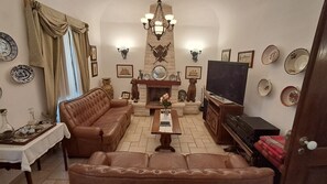 A living room with a sofa, television, fireplace, and decorative plates on the wall.