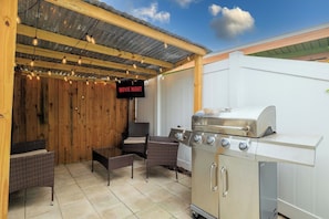 An outdoor patio with a grill, wicker furniture, and a 'MOVIE NIGHT' sign. - Coastal Getaway - 13 Min to Beach - Bike Trail (Belleair)
