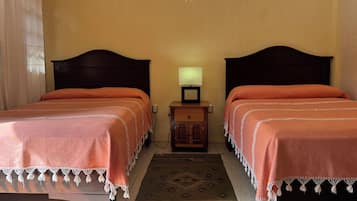 A room with two beds, a nightstand with a lamp, and a patterned rug.