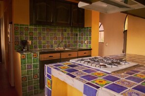 Una cocina con estufa a gas, un lavamanos y salpicadero de azulejos.