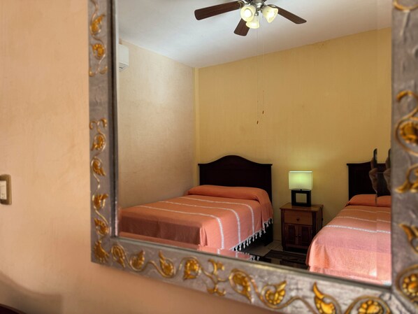Un dormitorio con cama, mesita de noche, lámpara y ventilador de techo.