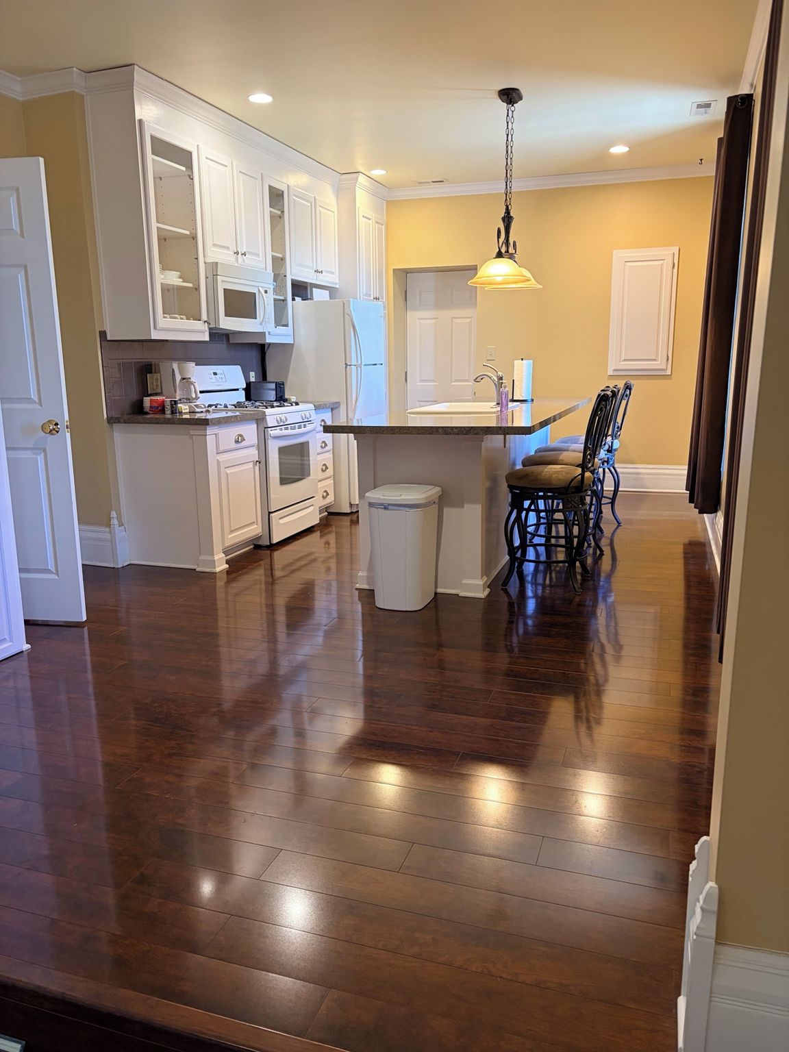 A kitchen with white cabinets, a stove, and a dining area with a table and chairs.