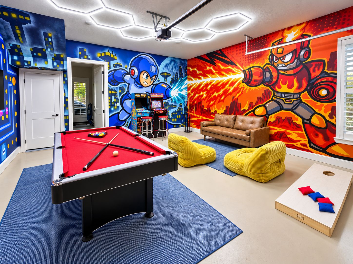 Een kamer met een pooltafel, een bank, loungestoelen en een muur met kleurrijke muurschilderingen.