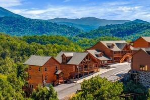 A lodge with multiple wooden cabins, a central building, and a view of surrounding mountains and forest. - Cubs Dream - Mountain Views・Private Indoor Pool・Theater・Hot Tub・Arcade & More! (Sevierville)