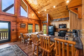 L’intérieur d’une cabane comprend une cuisine, un coin repas et une grande fenêtre donnant sur un paysage pittoresque.