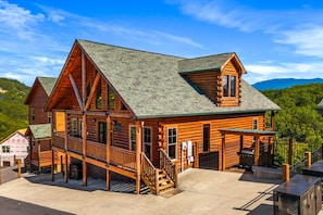 A log cabin with a porch, a staircase, and a view of the surrounding forest. - Cubs Dream - Mountain Views・Private Indoor Pool・Theater・Hot Tub・Arcade & More! (Sevierville)