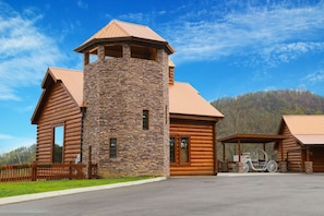 A log cabin with a stone tower, a covered porch, and a bicycle. - Cubs Dream - Mountain Views・Private Indoor Pool・Theater・Hot Tub・Arcade & More! (Sevierville)