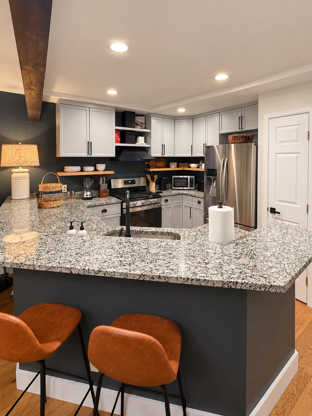 A modern kitchen with granite countertops, stainless steel appliances, and a central island with bar stools.