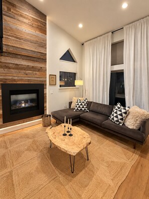 A modern living room with a fireplace, a sectional sofa, and a coffee table. - Cozy + Spacious 3BR/3.5BA townhome in Edwards perfect for your mountain getaway (Edwards)
