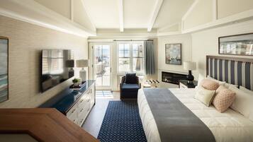 A hotel room with a bed, a desk, a TV, and a view of the sea.