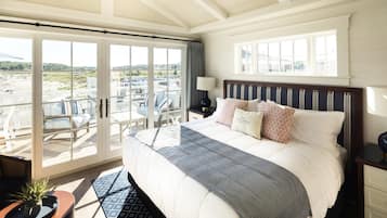 Habitación de hotel con una cama grande, vista a la playa y puerta corrediza de vidrio al exterior.