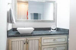 A bathroom with a white sink, a mirror, and a towel rack. - Destination Red Raiderland - Walk to TTU - 2BR/2BA (Lubbock)