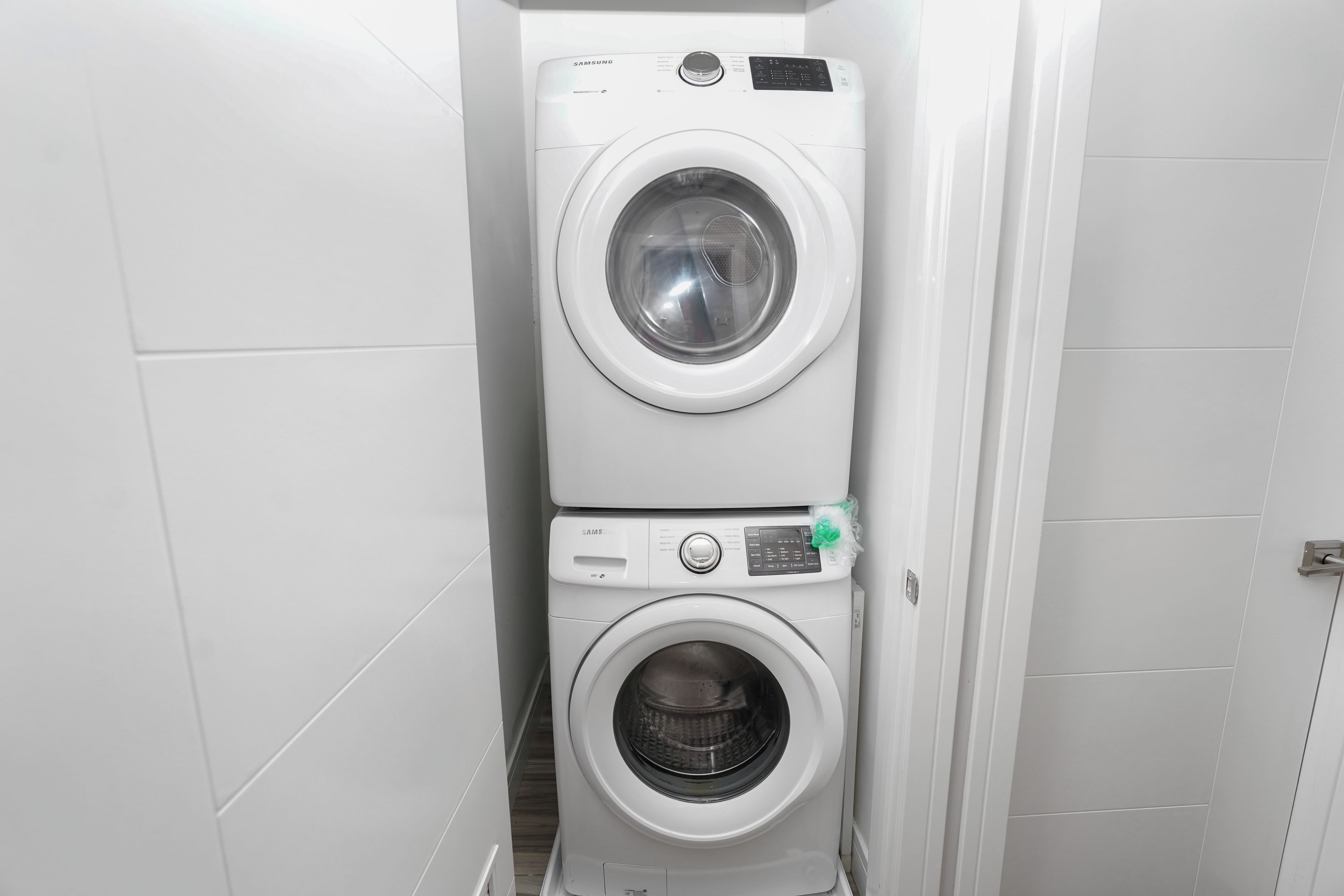 A compact, white laundry room with two stacked washing machines.