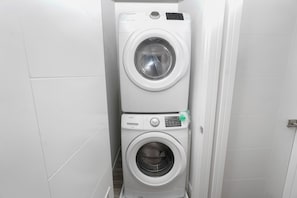 A compact, white laundry room with two stacked washing machines.