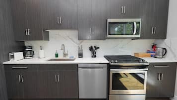 A modern kitchen with dark wood cabinets, a built-in microwave, a stainless steel dishwasher, and a gas stove.