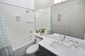 Un baño moderno con bañera, inodoro y tocador con espejo.