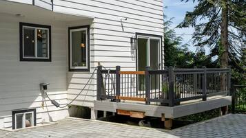 A white building with a wooden deck, a window, and a door.