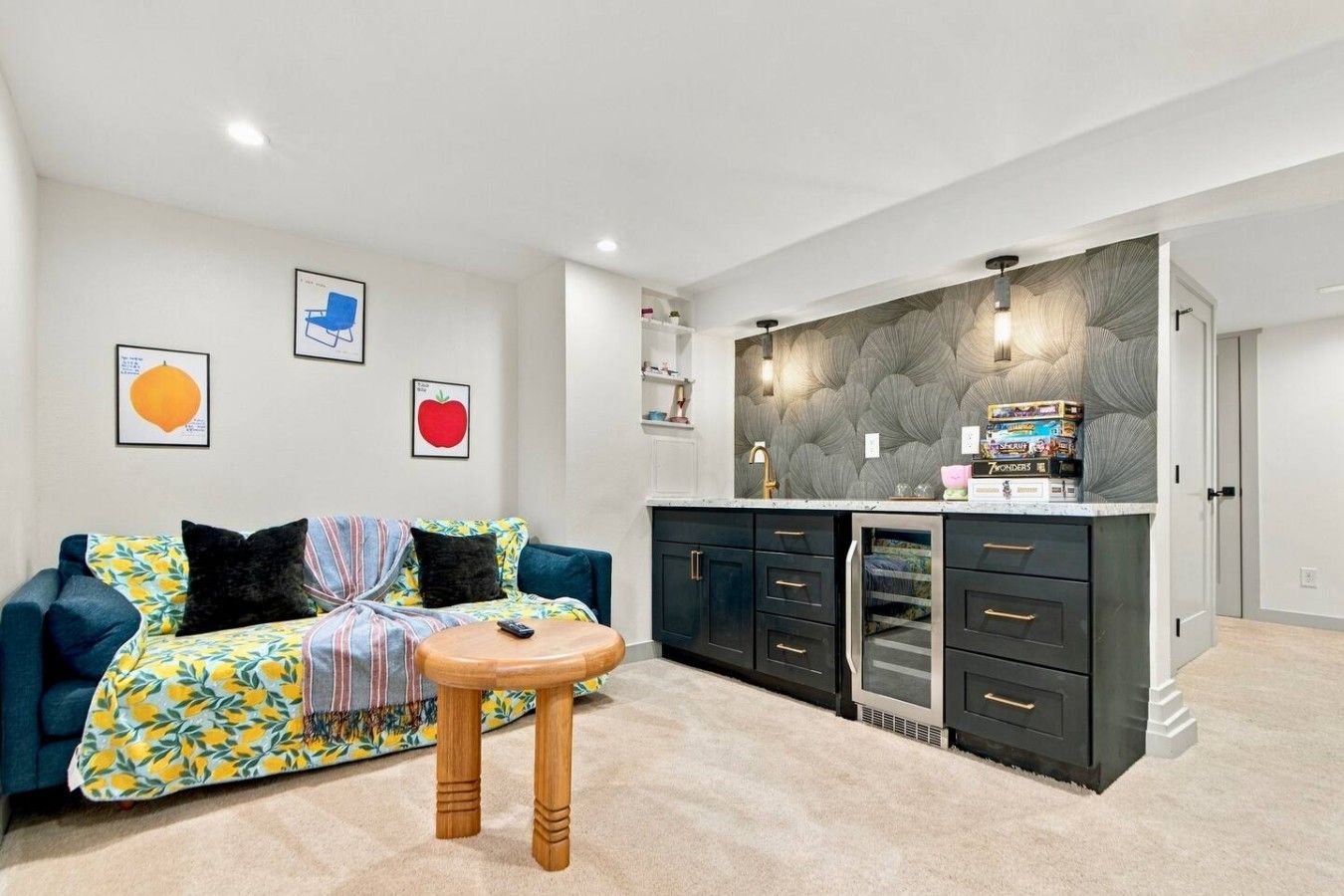A living room with a sofa, a coffee table, and a kitchen area with cabinets and a sink.
