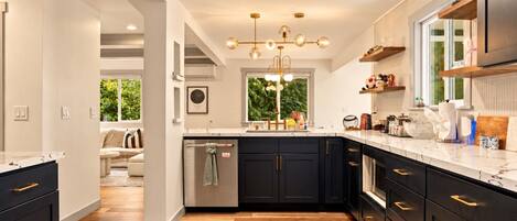 A modern kitchen with dark cabinetry, a marble countertop, and a central island.