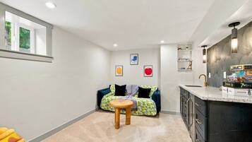 A compact living space with a kitchenette, a dining area with a small table, and a sofa with colorful cushions.
