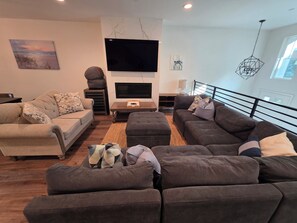 Una sala de estar moderna con un conjunto de sofás, un televisor de pantalla plana y un elemento decorativo en la pared.