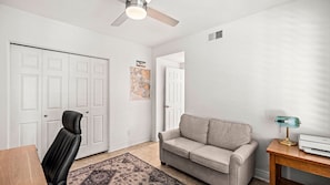 A room with a ceiling fan, a beige sofa, a black leather chair, a wooden table, and a rug. - Roadrunner Haven — warm and welcoming Monthly Rent (Scottsdale)
