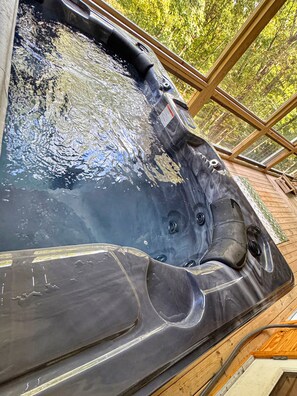 Una vasca idromassaggio con terrazza in legno e struttura in vetro.