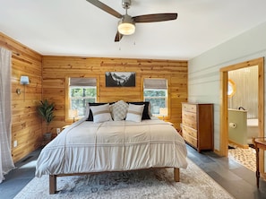 A bedroom with a bed, a ceiling fan, a window with a view, a dresser, and a door. - Graceland - Dogs OK | Hot Tub | Game Room | EV Charger (Blue Ridge)