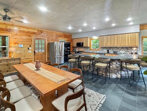 Eine moderne Küche mit Holzschränken, einer zentralen Kochinsel mit Barhocker, einem Kühlschrank und einer Mikrowelle.