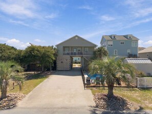 A two-story house with a front porch and a garage. - Sherry's Paradise: 4BR OKI Retreat, Heated Pool, Ocean Views, 2 Dogs Welcome! (Oak Island)