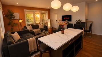 A modern living room with a sofa, coffee table, and a TV displaying 'NETFLIX'.