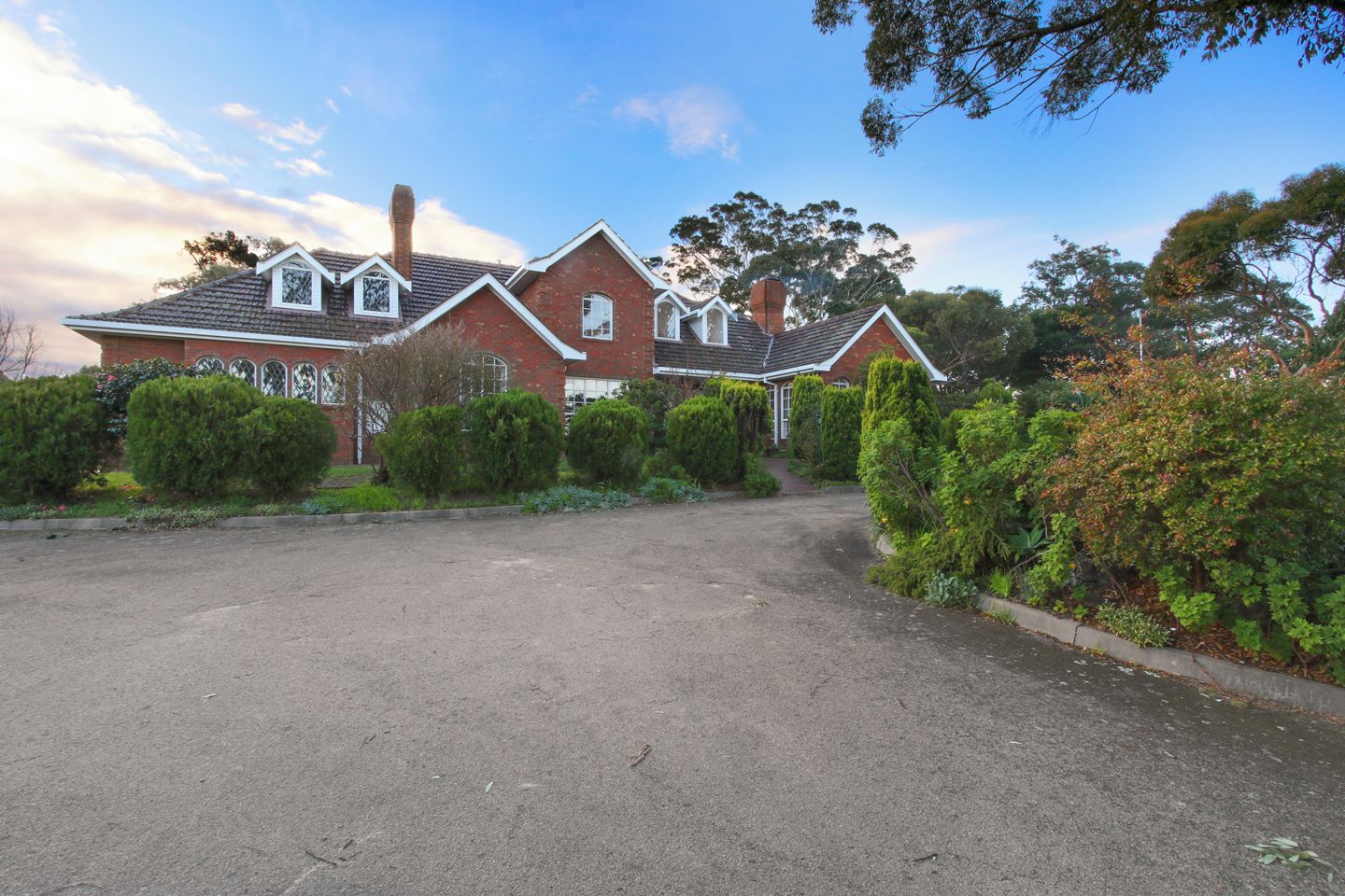 A two-story brick house with a driveway and well-maintained landscaping.