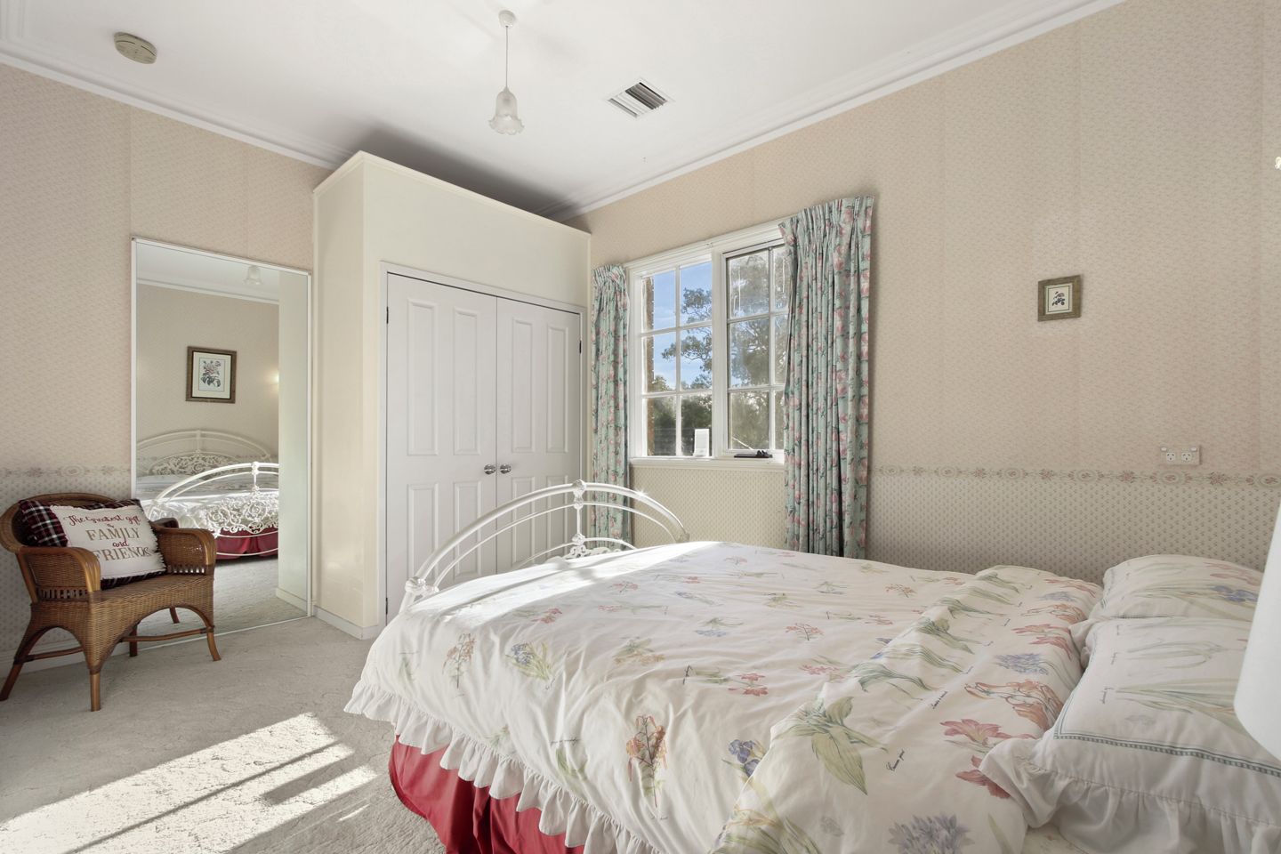 A bedroom with a bed, a chair, a wardrobe, and a window with curtains.