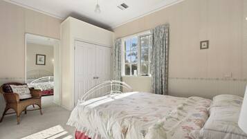 A bedroom with a bed, a chair, a wardrobe, and a window with curtains.