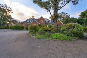 A two-story house with a brick exterior, a chimney, and a driveway leading to a parking area.