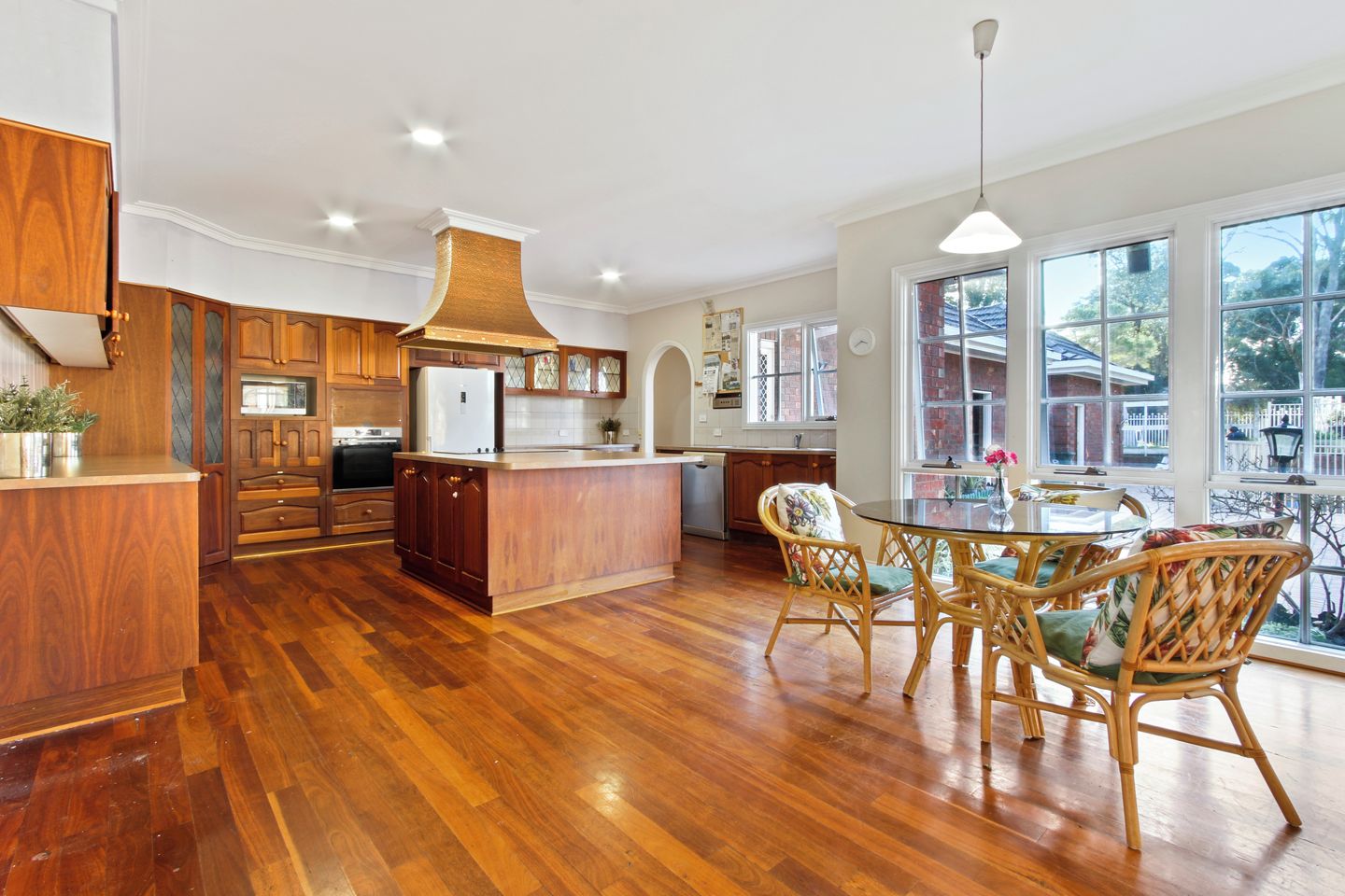 A spacious kitchen with wooden cabinets, a central island, and a dining area with wicker chairs.