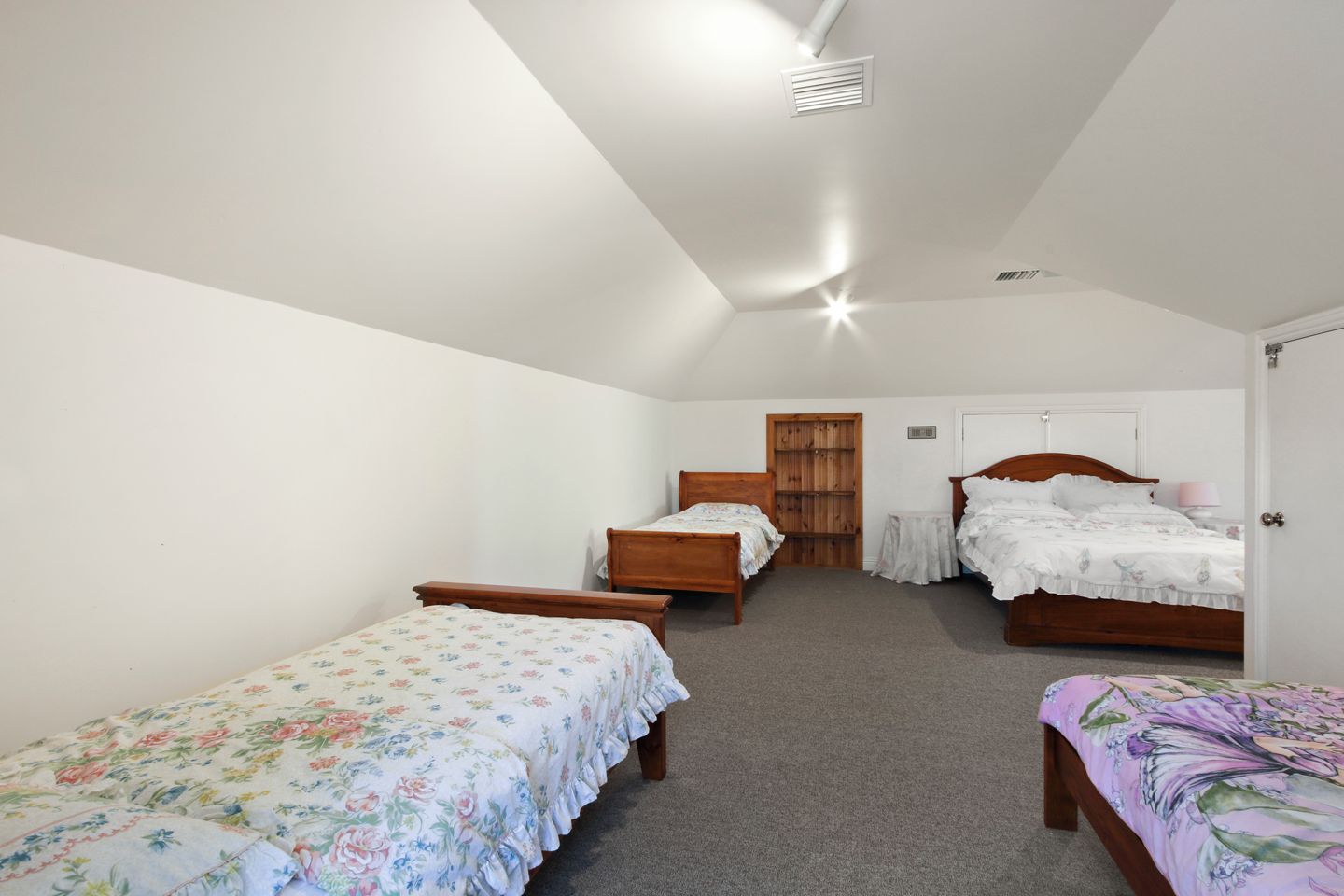 A bedroom with two single beds, a double bed, a small table, and a wardrobe.