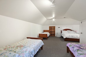 A bedroom with two single beds, a double bed, a small table, and a wardrobe.